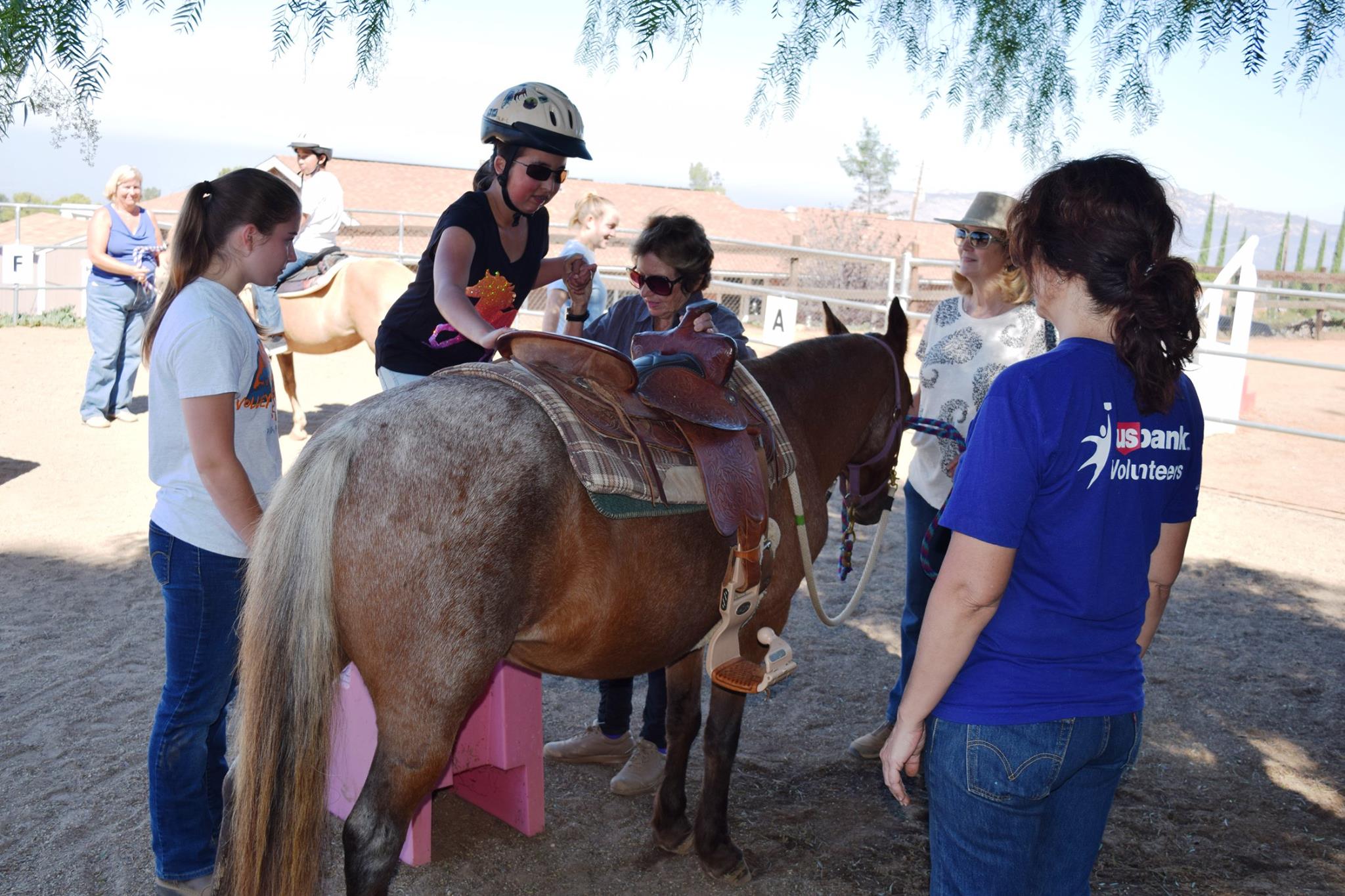 Volunteers help student mount pony